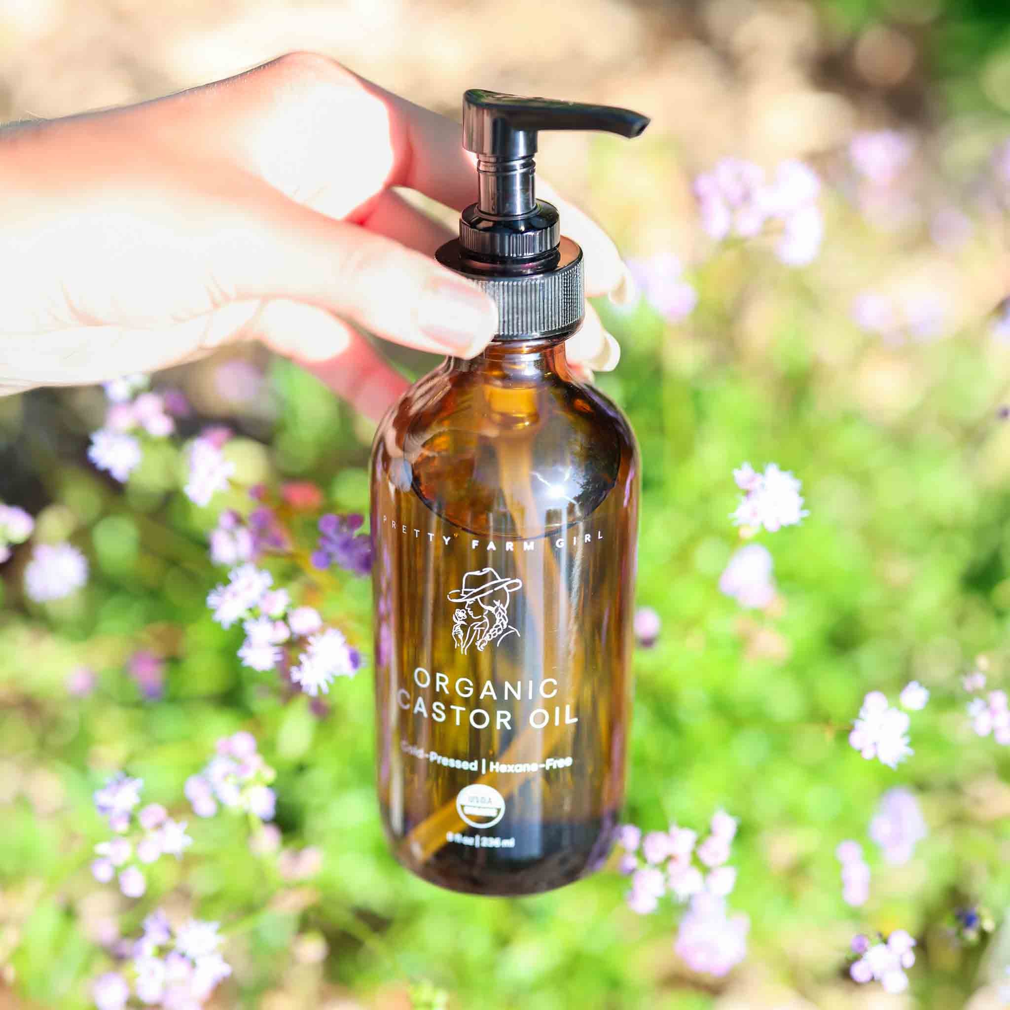 Hand holding a bottle of 'Organic Pastor Oil' with a blurred natural background