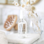 Clear bottle with dropper labeled Clarifying Facial Toner on a neutral background