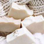 Close-up of 4 goat milk and tallow soap bars with a textured fabric background.