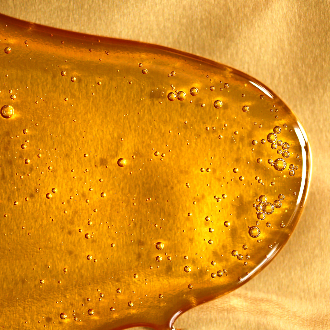 Close-up of a droplet of honey with bubbles on a gold background
