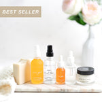 Collection of skincare products including bottles and a jar on a marble surface with flowers in the background.