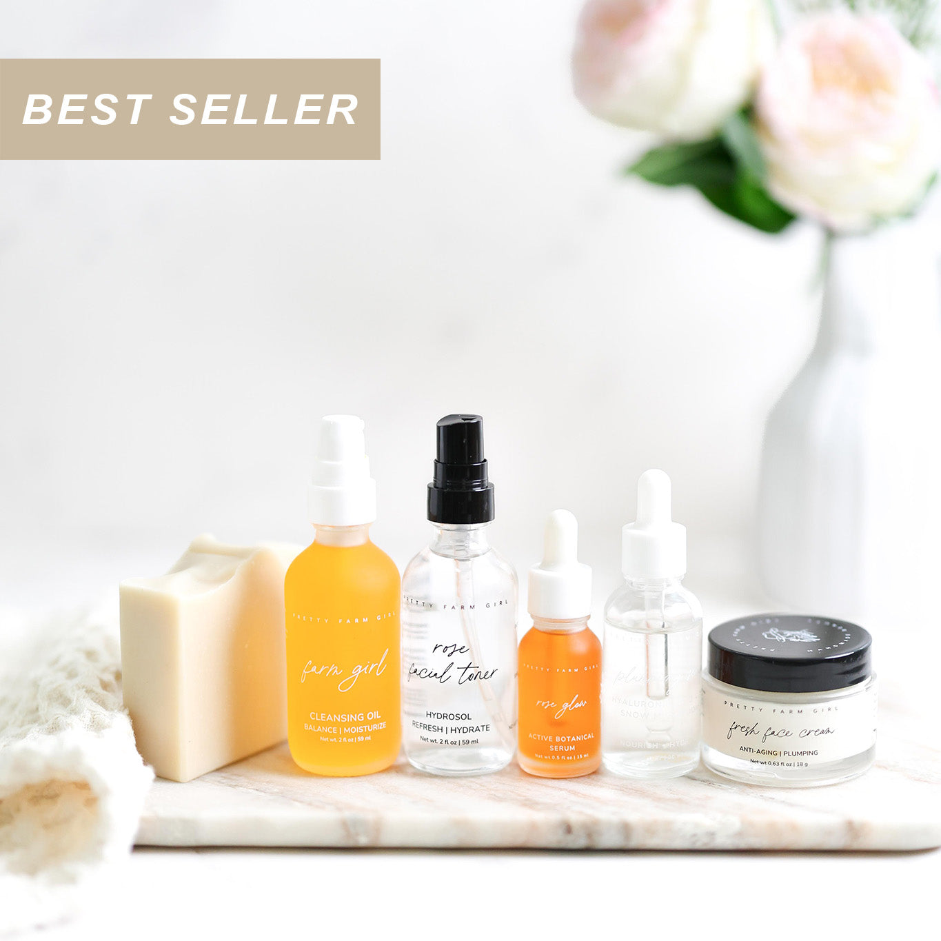 Collection of skincare products including bottles and a jar on a marble surface with flowers in the background.