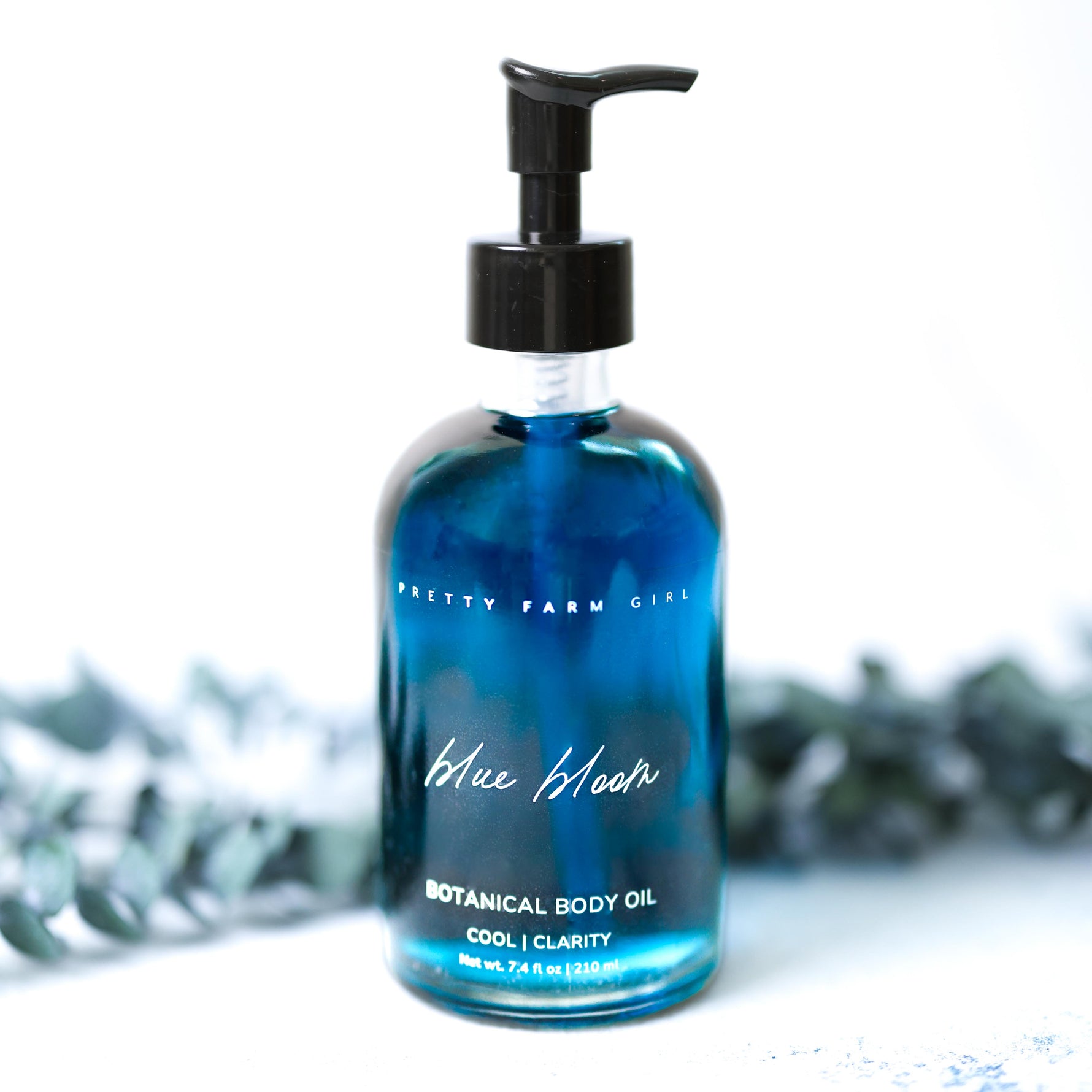 Blue bottle of botanical body oil with a pump on a white background