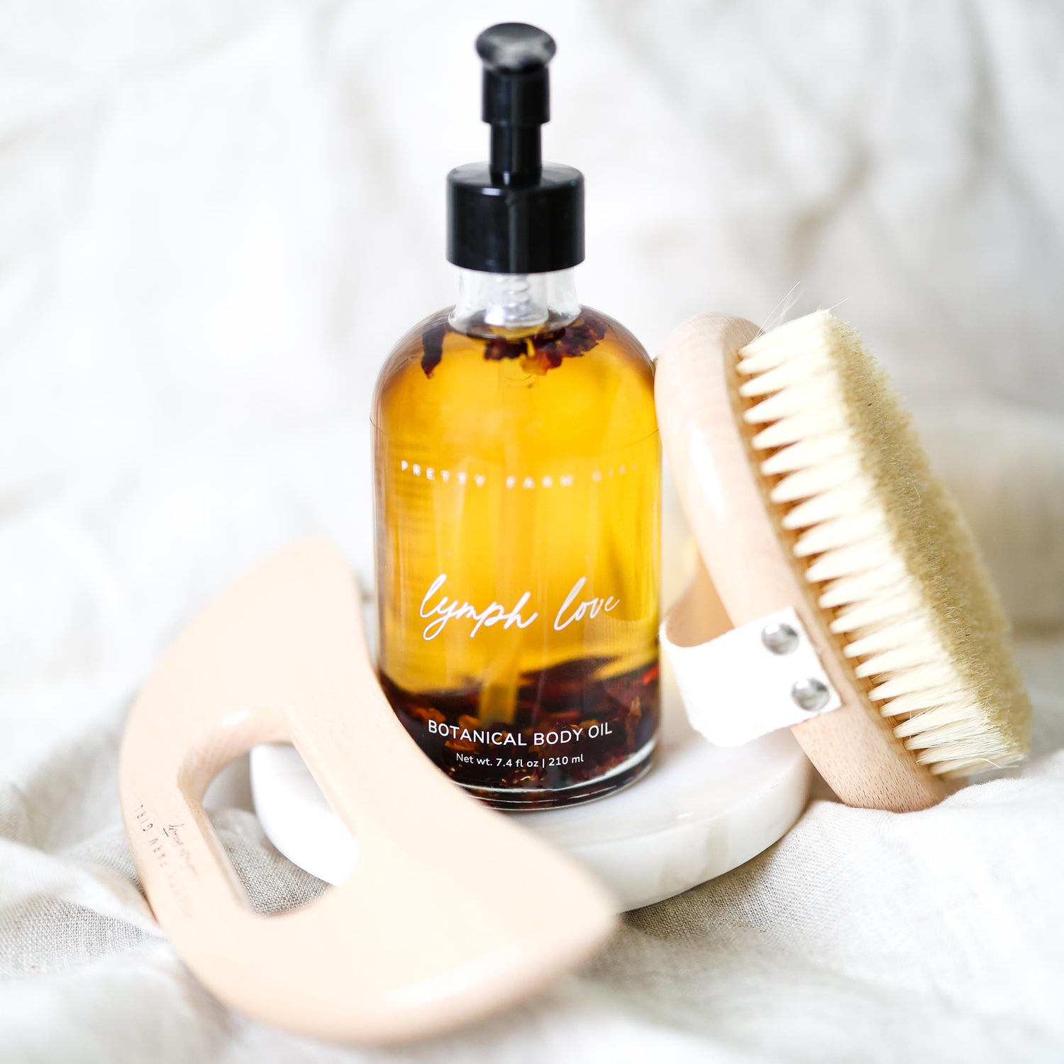 Bottle of 'Lymph Love' botanical body oil with a brush on a white background