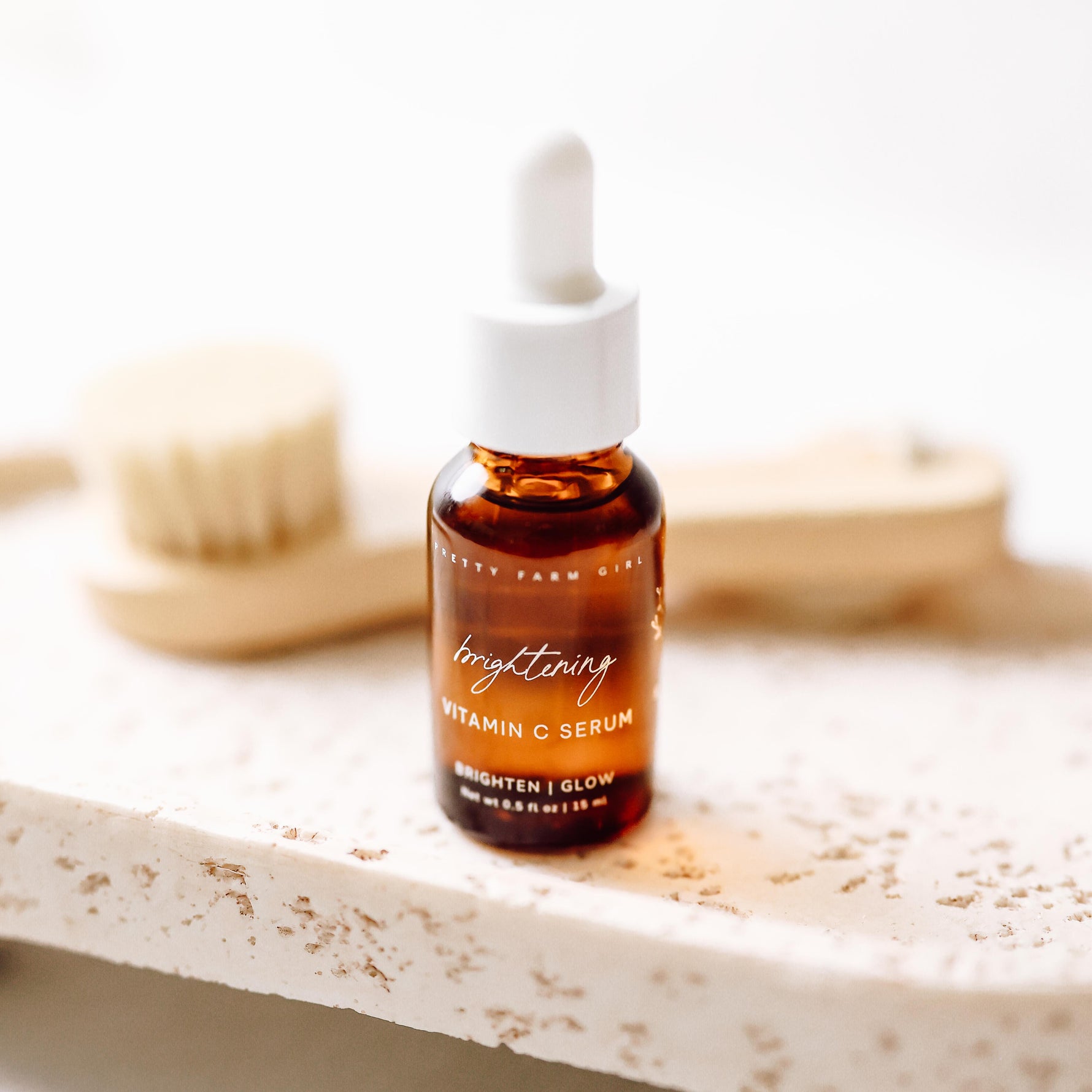 Brightening Vitamin C Serum bottle on a white stone surface with a soft neutral background