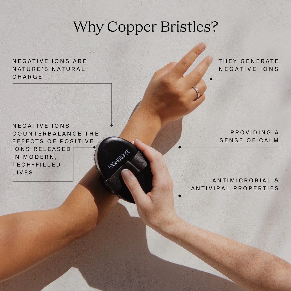 Person using a black Higherdose body brush with text explaining copper bristle benefits on a light gray background