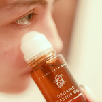 Close-up of a bottle of Pretty Farm Organic Castor Oil being applied to skin.