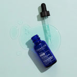 Blue serum bottle with dropper on a light green background