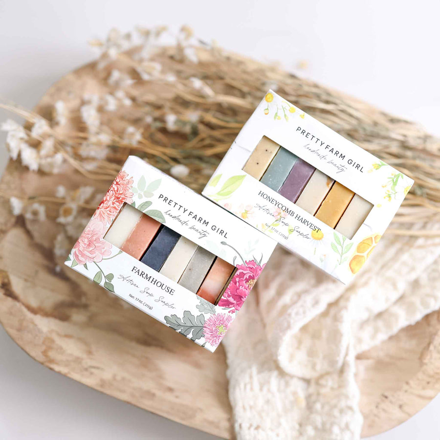 Two Pretty Farm Girl Soap samplers on a decorative plate with flowers. Soap Sampler boxes shown are Farmhouse Artisan Soap Sampler and Honeycomb Harvest Artisan Soap Sampler. 
