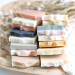 Stack of various colored sample sized soap bars on a woven surface