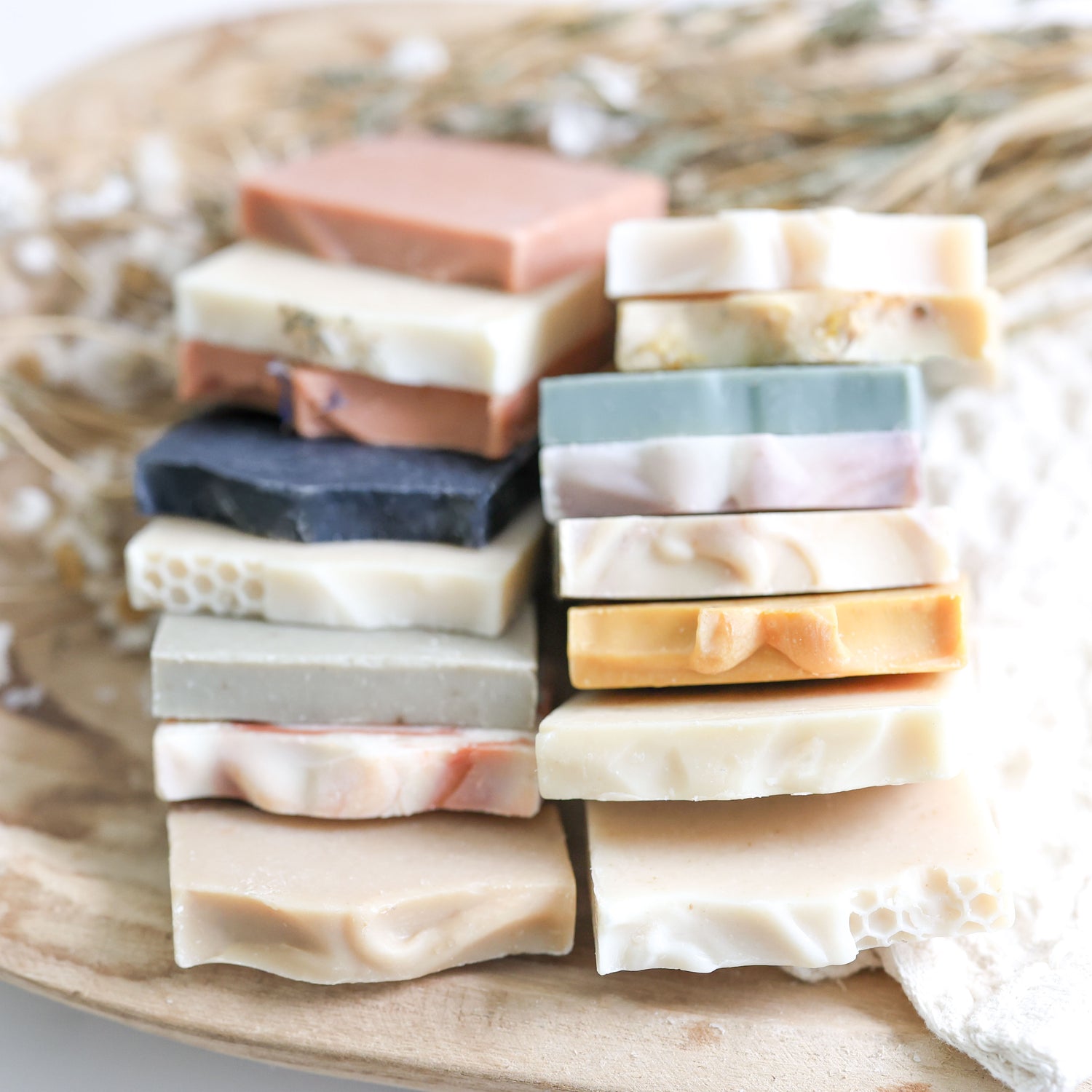 Stack of various colored sample sized soap bars on a woven surface