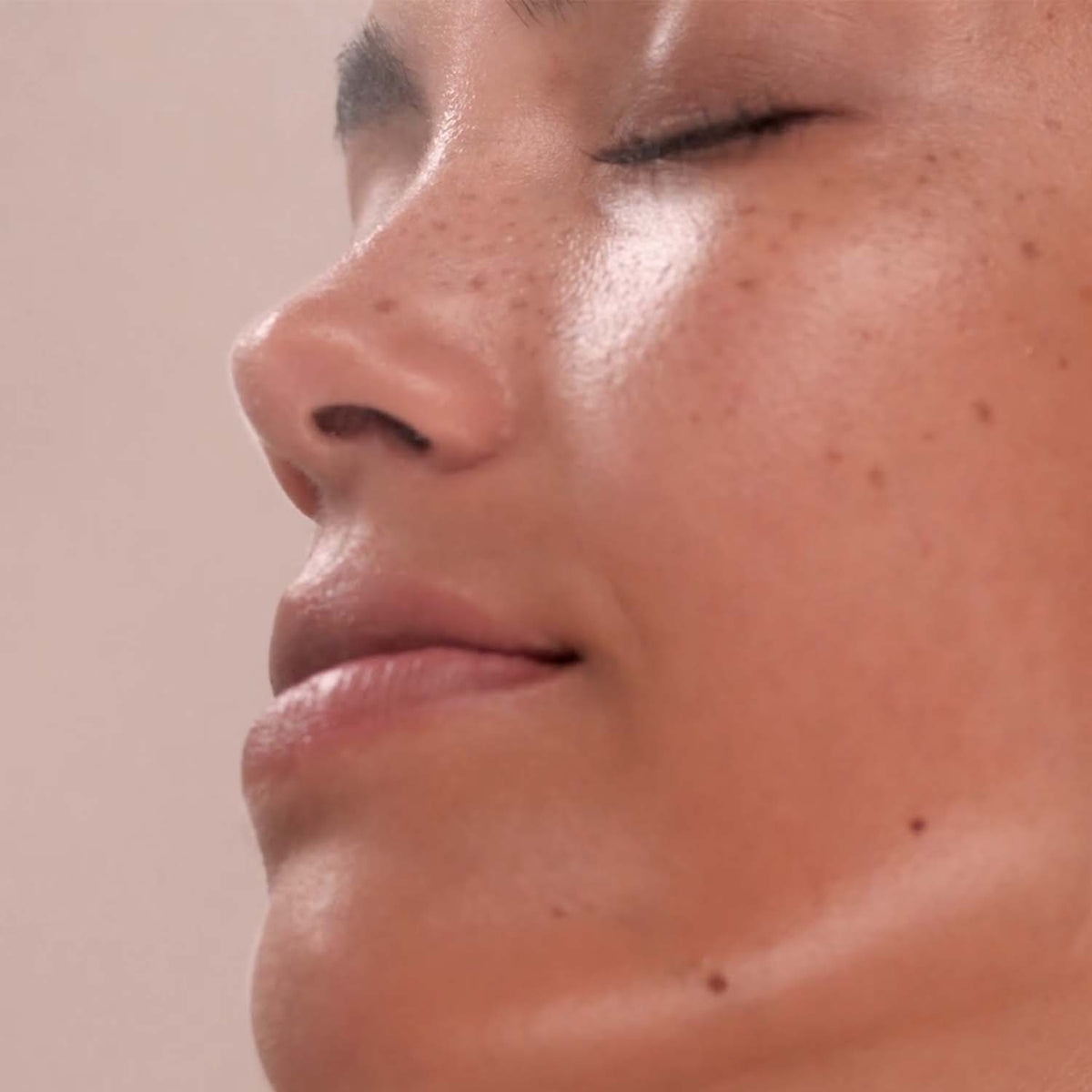 Close-up of a person's face with a neutral expression on a beige background