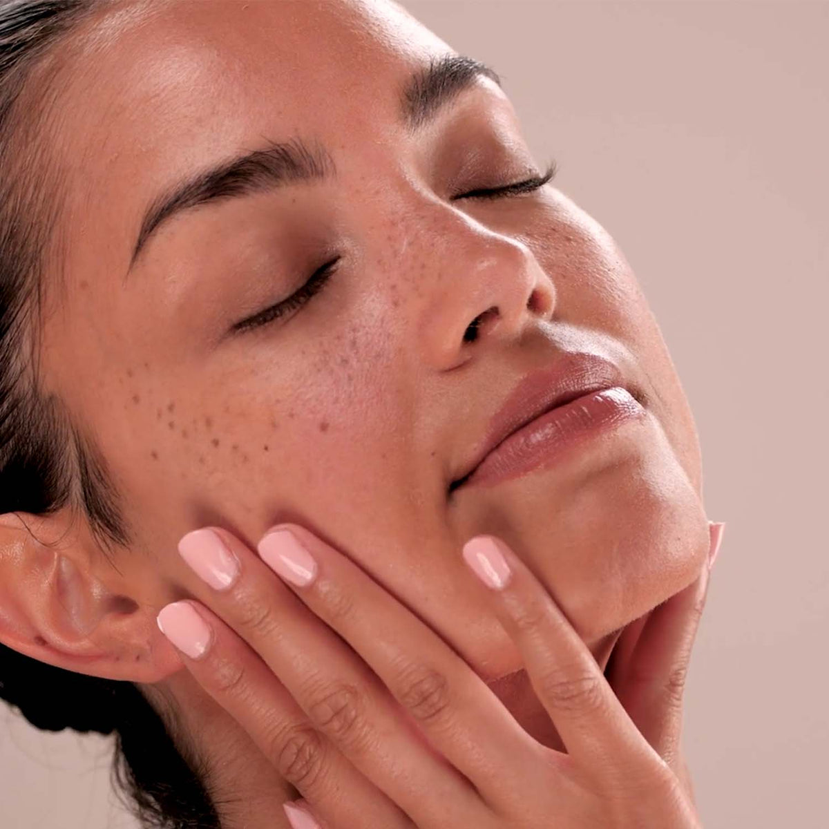 Close-up of a person with their hand near their face on a neutral background
