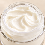 Close-up of Fresh Face Cream's whipped white texture swirled inside an open glass jar.