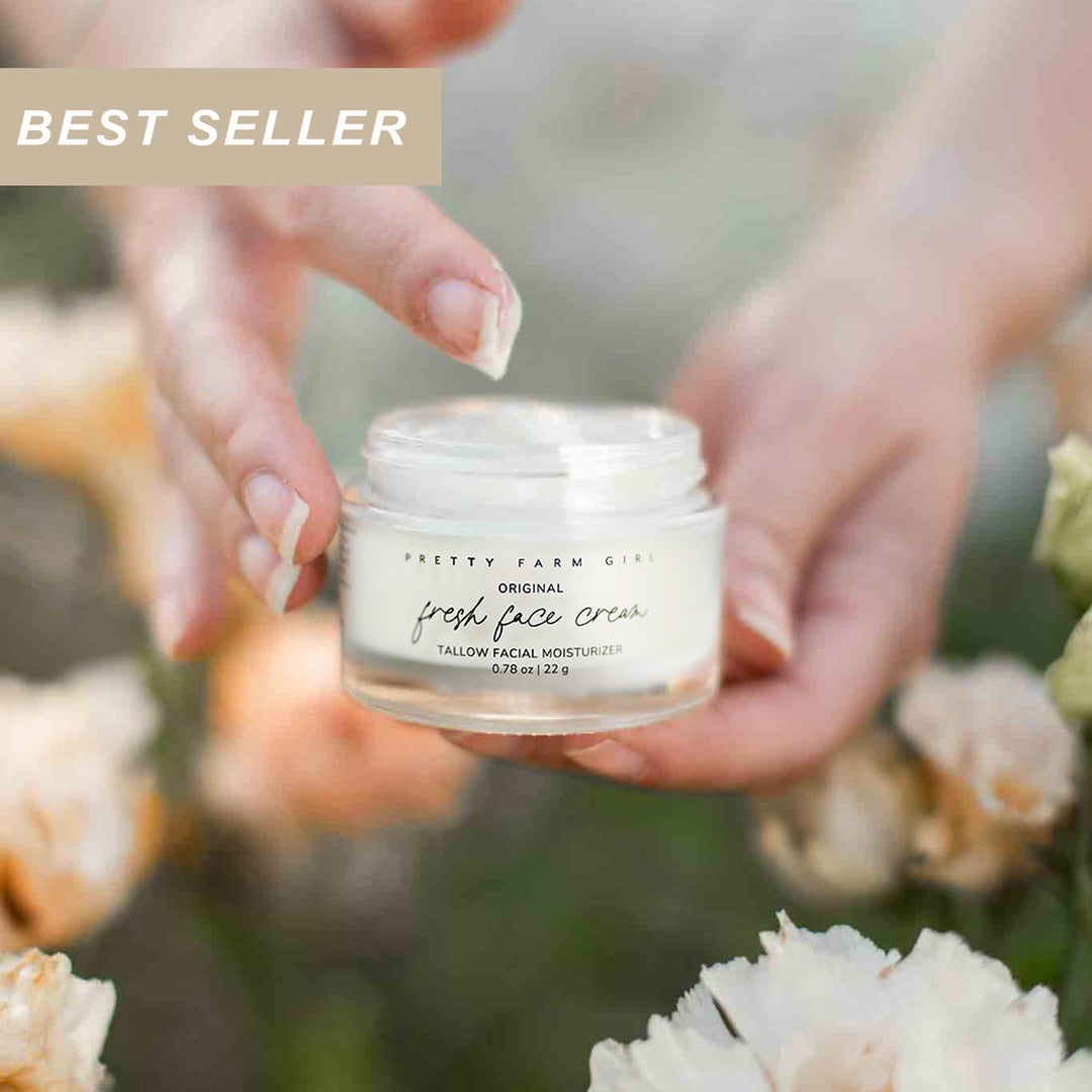 Person holding a jar of 'Pretty Farm' fresh face cream with flowers in the background