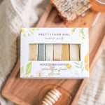 Box of Pretty Farm Girl honeycomb harvest soap sampler on a wooden tray with honeycombs and a honey stirring stick.
