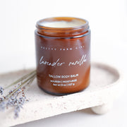 Pretty Farm Girl Lavender Vanilla Tallow Body Balm jar on a white stone surface with lavender botanical accents.