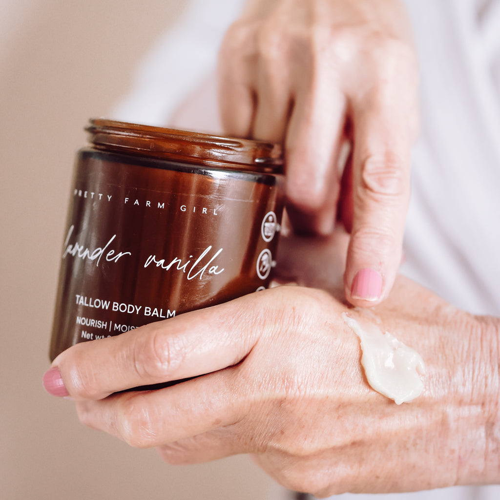 Pretty Farm Girl Lavender Vanilla Tallow Body Balm jar held above a hand with balm texture.