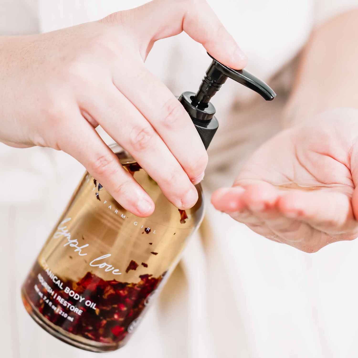 Lymph Love Natural Body Oil dispensed onto hand for body massage