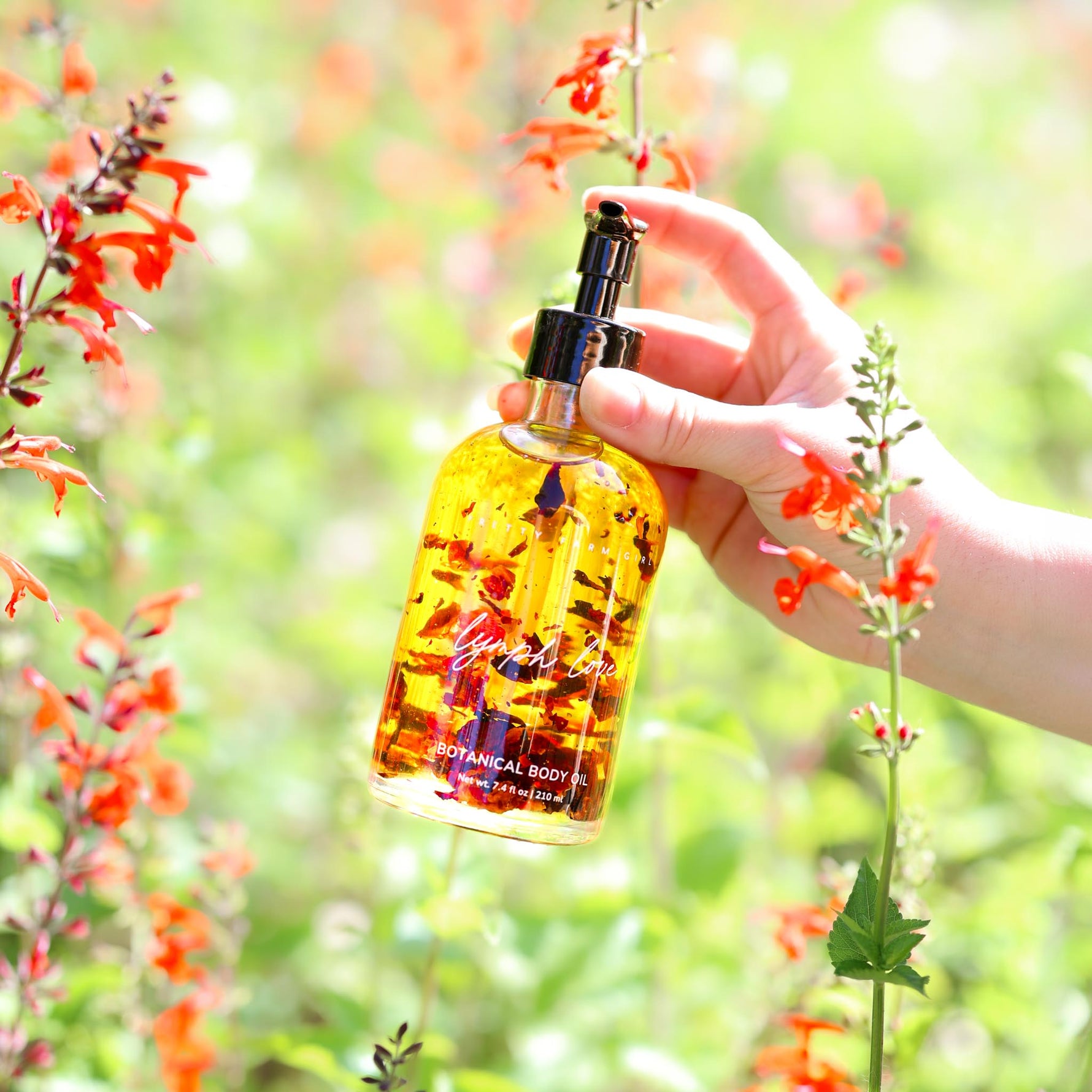 Hand holding a bottle of yellow liquid with a blurred natural background