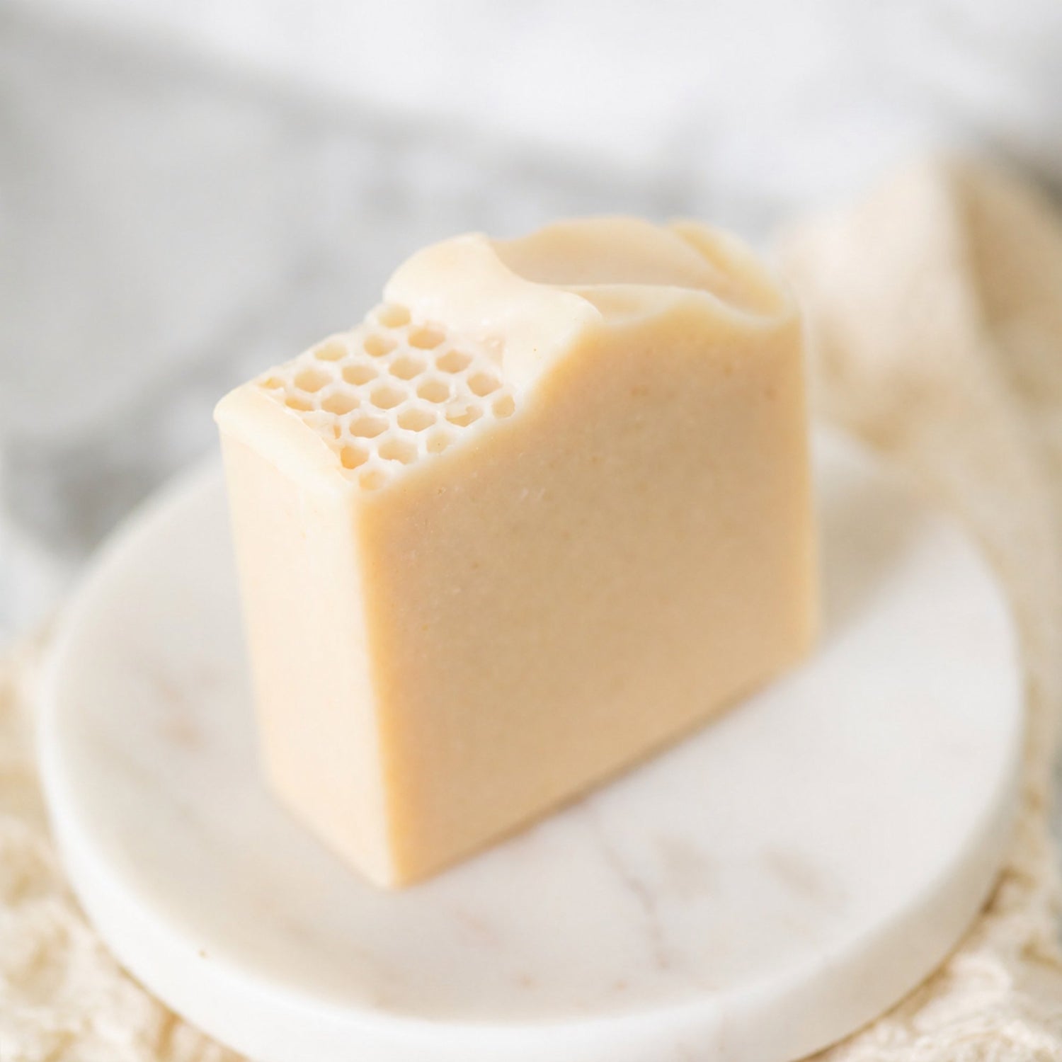 A rectangular bar of Milk & Honey Fragrance Free soap with a honeycomb pattern on one end, displayed on a small round white marble dish.