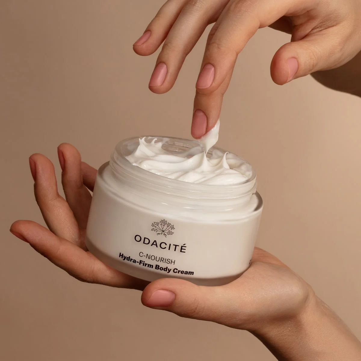 Person using Odacite body cream to their hand with a beige background