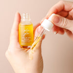 Plum Glow Multipurpose Face Serum dropper applying golden plum oil onto the back of a hand