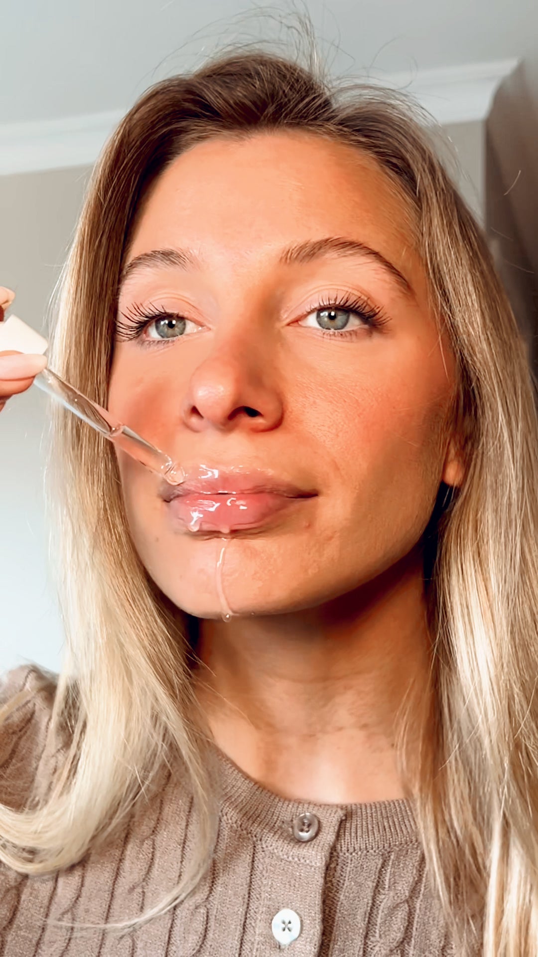 Woman applying Plumping Hyaluronic Acid to her lips with a dropper.