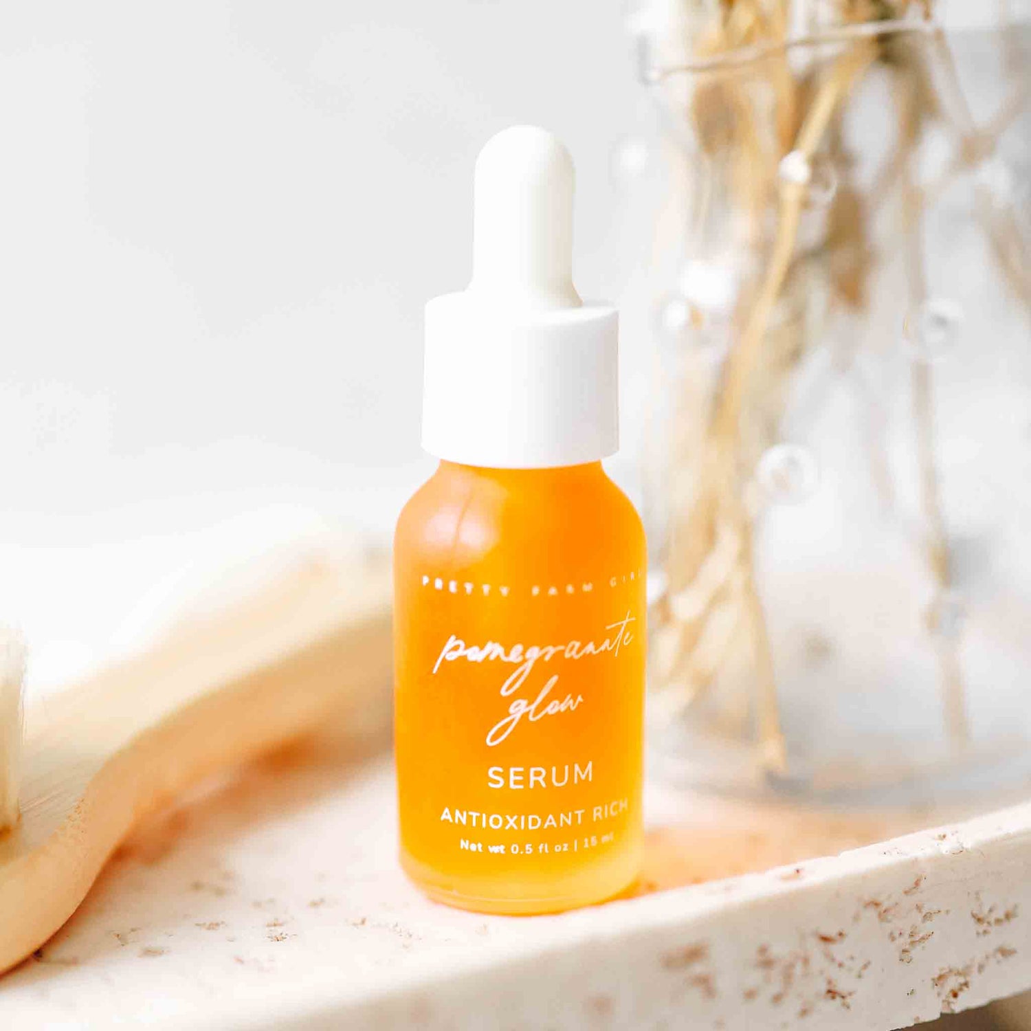 Pomegranate Glow Natural Skin Protecting Serum bottle displayed on a marble tray with soft skincare decor
