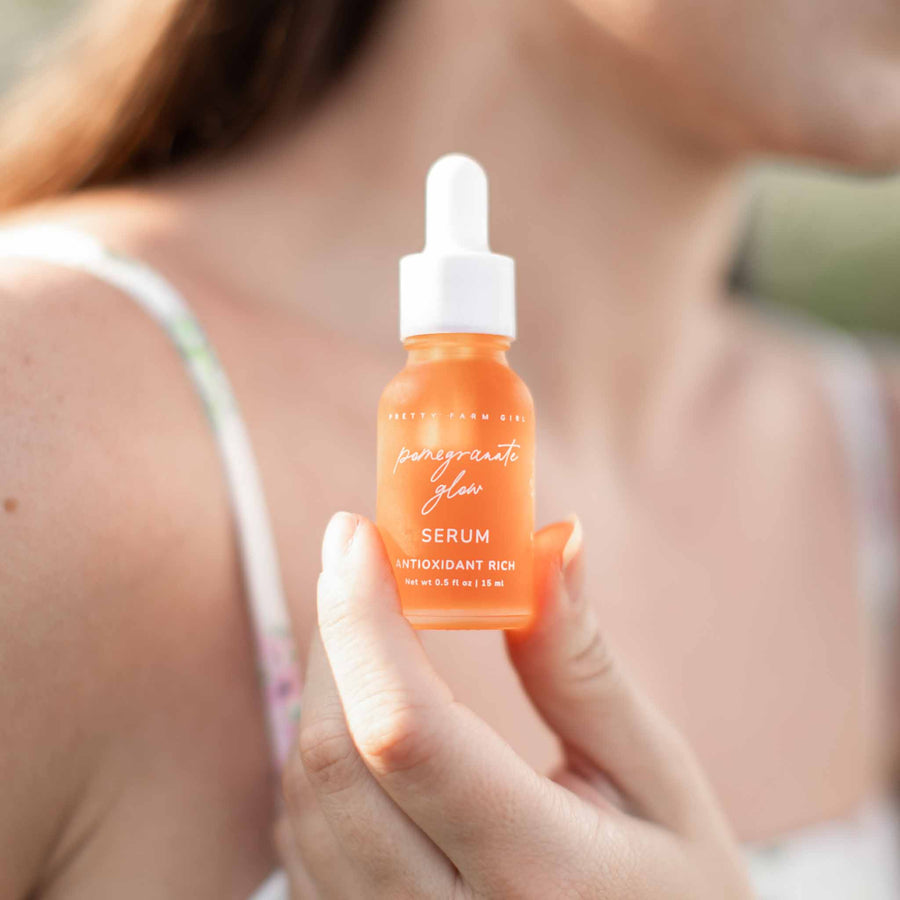 Pomegranate Glow Natural Skin Protecting Serum bottle held in hand with a soft lifestyle background