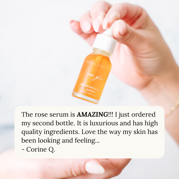 Hand holding a bottle of rose serum with a positive review text overlay that says "The rose serum is AMAZING!!! I just ordered my second bottle. It is luxurious and has high quality ingredients. Love the way my skin has been looking and feeling... by Corine Q."
