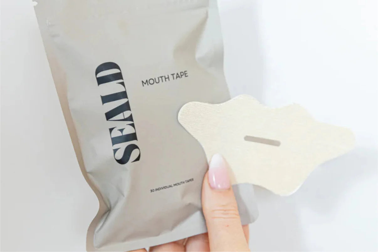 Mouth tape packaging with a piece of tape held by a hand on a light background
