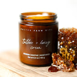 Jar of Tallow + Honey Cream by Pretty Farm Girl with honeycomb and honey on a wooden surface.