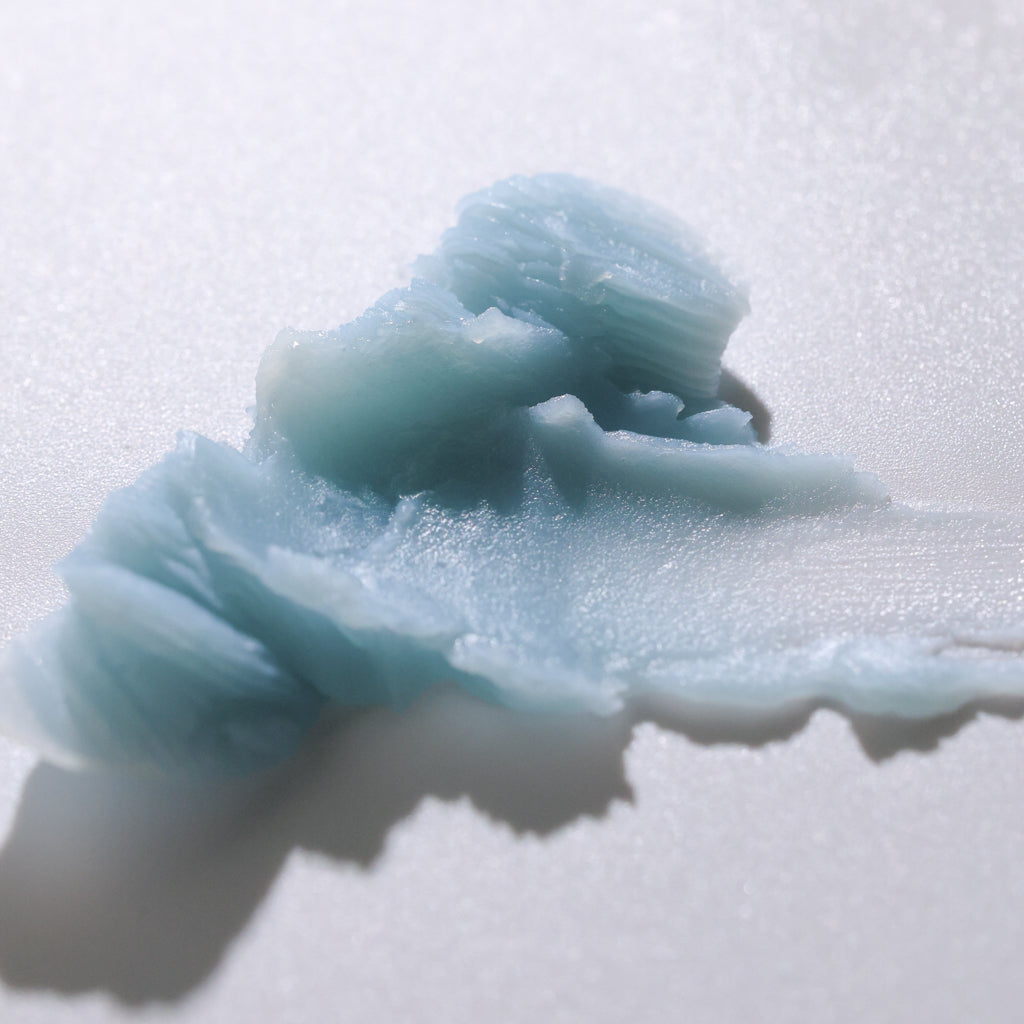 Close-up of Pretty Farm Girl Blue Beauty Balm blue texture on a neutral background.