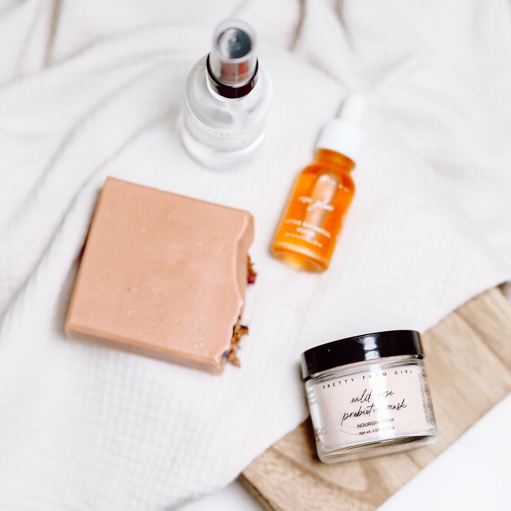 Skincare products including jars and a bottle on a white fabric background