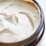 Close-up of a tallow body butter jar with the top off showing the texture of the whipped tallow cream