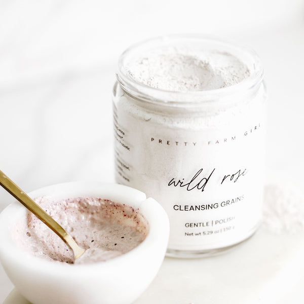 Wild Rose Facial Cleansing Grains in glass jar with mixed cleanser and spoon