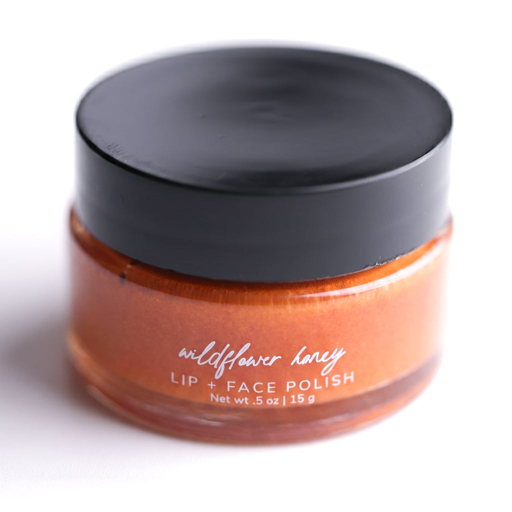 Pretty Farm Girl Wildflower Honey Lip & Face Polish jar with black lid on a white background.