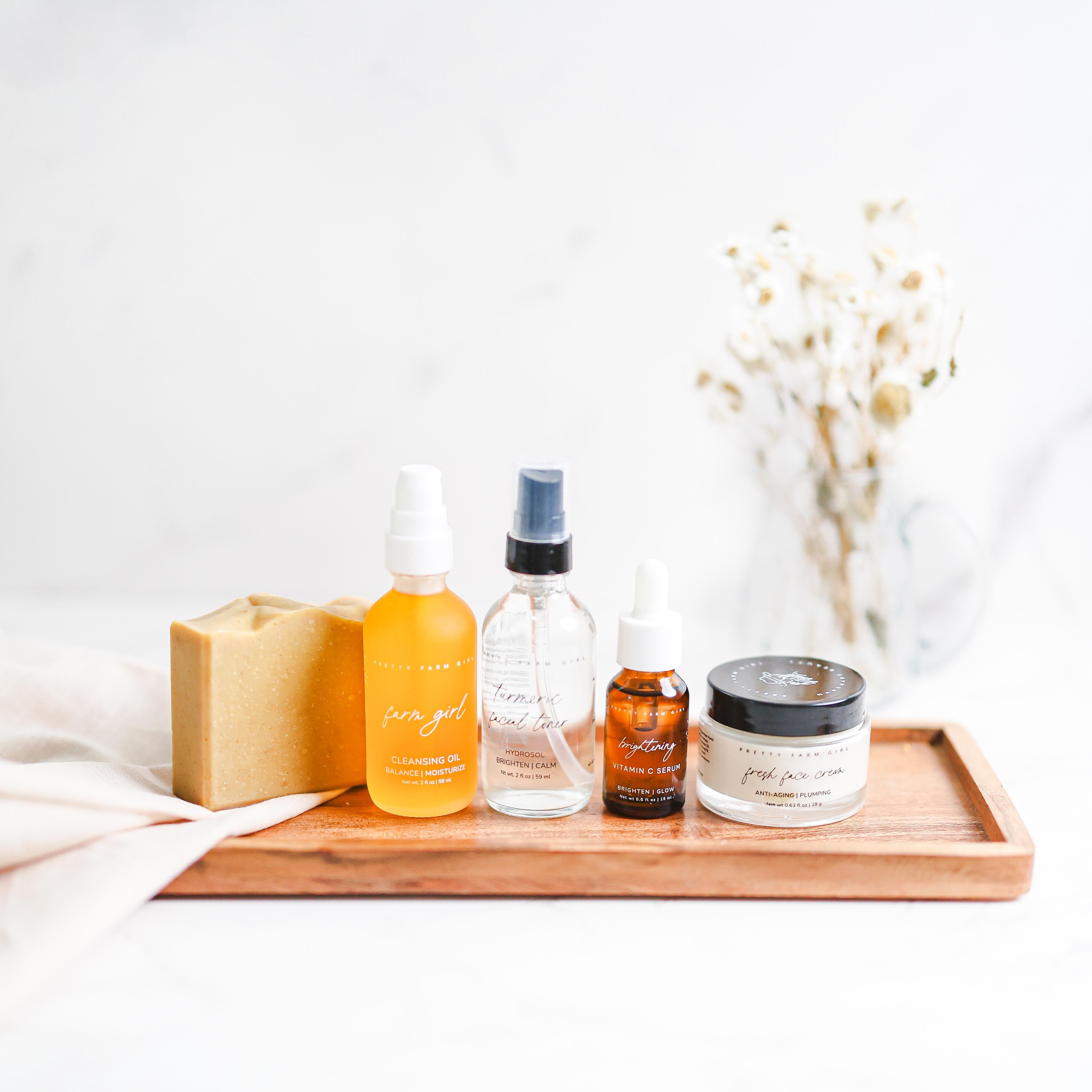 Collection of skincare products on a wooden tray with a white background