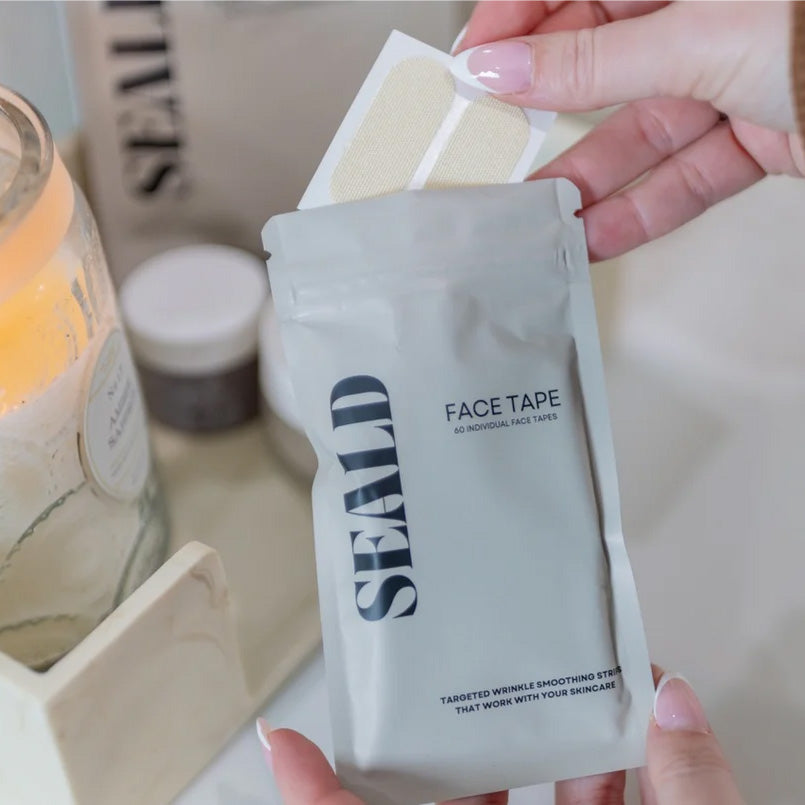 Hand holding a package of 'SEALD' face tape with a blurred background
