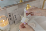 Person holding thin face tape over a sink with candles and books in the background