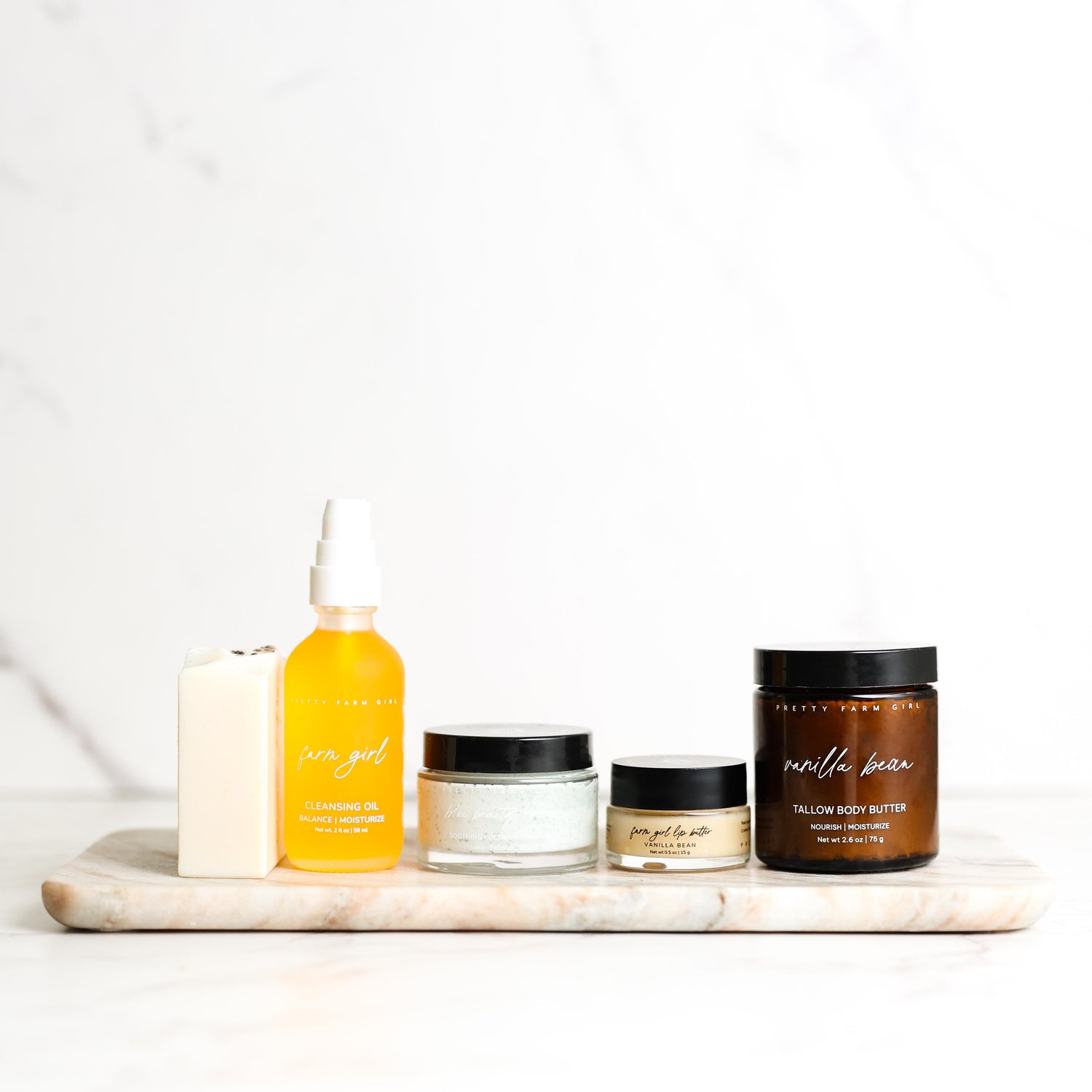 Collection of skincare products on a marble tray with a white background