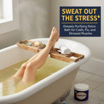 Person relaxing in a bathtub with a bath tray, candle, and towel, with text saying Sweat the stress deeply purifying detox bath for colds, flu, and stressed muscles.