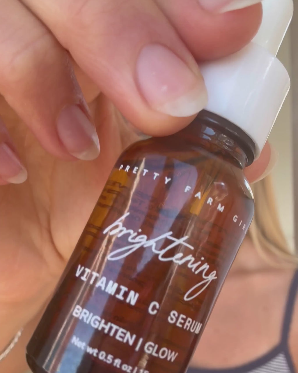 Video showing a close-up of the Brightening Vitamin C Serum bottle and a woman applying it to her face