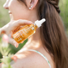 Pure Growth Hair Serum bottle held near long hair outdoors with a soft natural background