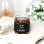 Jar of honey from Pretty Farm Girl Raw Artisan Wildflower Honey on a white surface with a blurred background