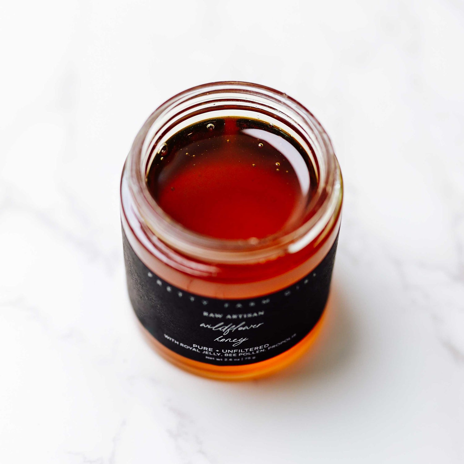 Jar of honey with a black label on a white background