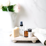 Pretty Farm Girl's Rooted and Ready Kit, showing 4 products including a Fresh Face Cream Soap Bar, 2oz Rose Facial Toner, .5oz Brightening Vitamin C Serum, .5oz Tallow + Honey Fragrance Free Lip Butter in an Eco-Friendly paper tube on a tray with a blurred vase in the background.